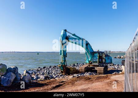 A blue Kobelco SK350 excavator on the seafront works on coastal defences in Southsea, Portsmouth, a holiday resort on the Solent, south coast England Stock Photo