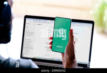 Man using ChatGPT in the mobile phone and the laptop. This app is a chatbot based on Artificial Intelligence developed by OpenAI. ROSARIO, ARGENTINA - Stock Photo