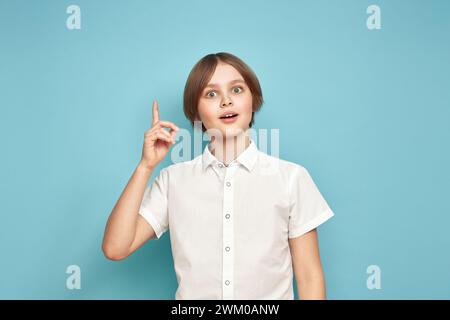 Portrait of cheerful teen boy with good idea isolated over blue background Stock Photo