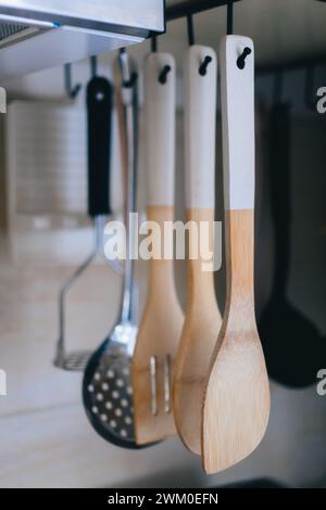 Wooden spoons hanging on hooks in a kitchen Stock Photo
