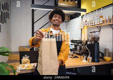 Smiling barista holding takeaway bag at coffee shop Stock Photo