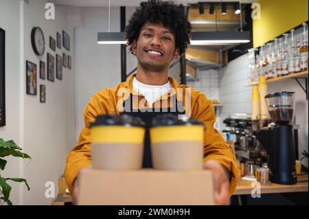Smiling barista holding takeaway coffee cups at cafe Stock Photo