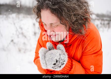 Mature woman shivering in snowfield wearing mittens Stock Photo