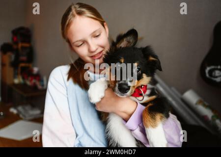 Girl holding dog in arms at home Stock Photo