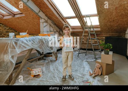 Girl showing drawing on sketch pad in room under renovation Stock Photo