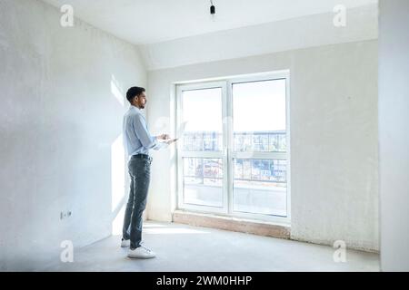 Architect using laptop and standing near window at site Stock Photo
