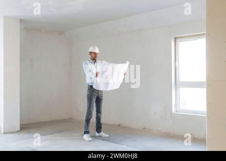 Architect examining blueprint at construction site Stock Photo