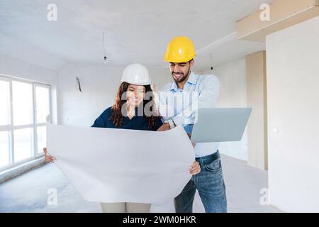 Happy architects discussing over blueprint at site Stock Photo