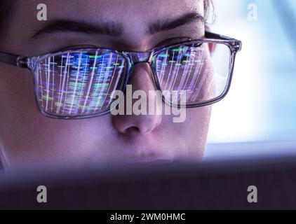 Scientist wearing eyeglasses and analyzing DNA data on computer Stock Photo