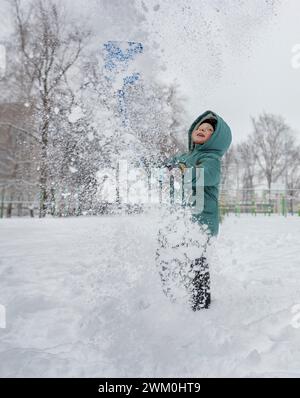 Playful boy throwing snow in air at park Stock Photo