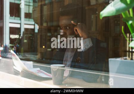 Shocked businessman reading newspaper seen through glass Stock Photo