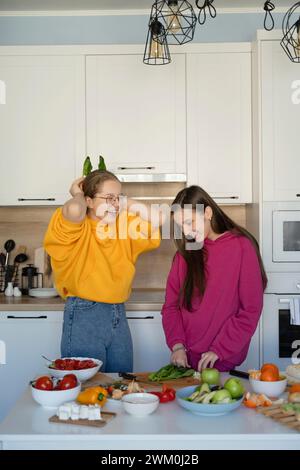 Cheerful friends preparing food in kitchen at home Stock Photo