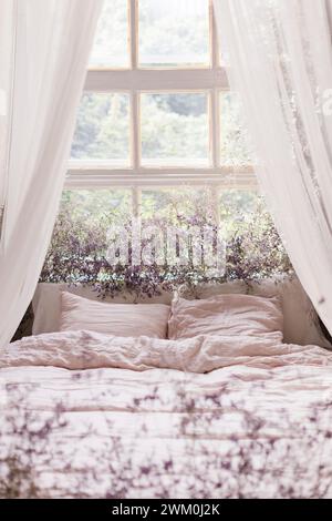 Bed near window decorated with dried flowers Stock Photo