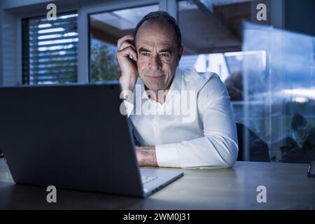 Smiling freelancer having video call on laptop at home office Stock Photo