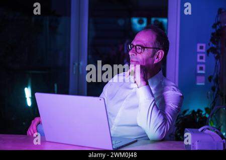 Thoughtful freelancer leaning on elbow near laptop at home office Stock Photo