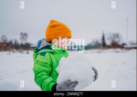 Smiling boy holding snowball in winter Stock Photo