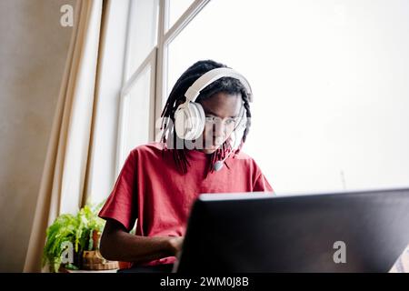 Young man wearing headset and using laptop at home Stock Photo