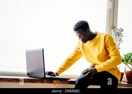 Man using laptop near window at home Stock Photo