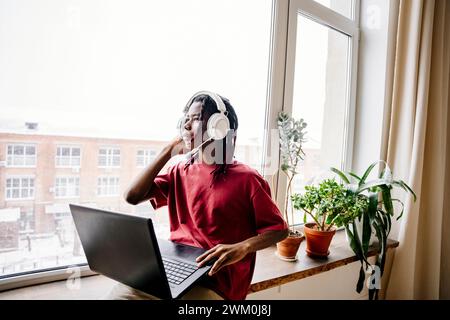 Man wearing headset and sitting with laptop at home Stock Photo
