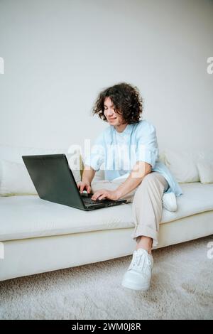 Happy young man using laptop on sofa at home Stock Photo