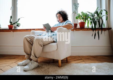 Man sitting on armchair and using tablet PC at home Stock Photo