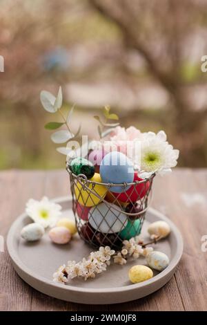 Colorful Easter eggs with flower decoration in basket on tray Stock Photo