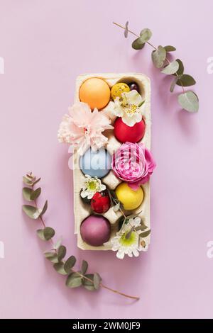Colorful Easter eggs in carton decorated with flowers over pink background Stock Photo