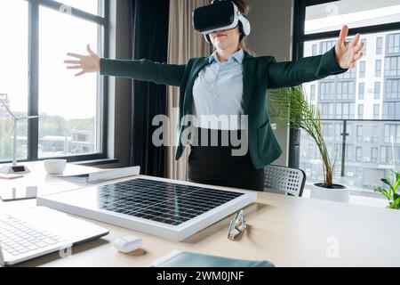 Engineer wearing virtual reality headset with arms outstretched in office Stock Photo
