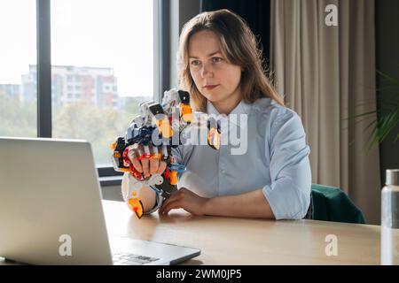 Engineer working on robot arm project and using laptop in office Stock Photo