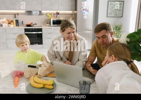 Father using smart phone with family having breakfast at dining table Stock Photo