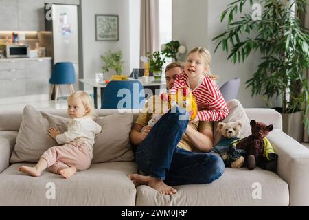Father sitting with children on sofa at home Stock Photo