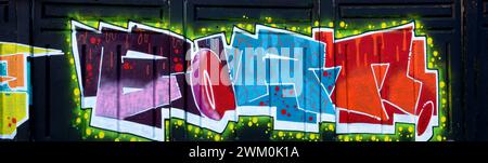 The old wall decorated with paint stains in the style of street art culture. Colorful background of full graffiti painting artwork with bright aerosol outlines on wall. Colored background texture Stock Photo