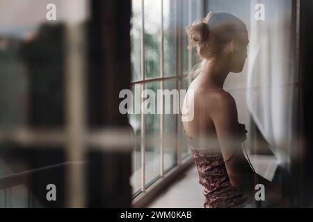 Pensive woman sitting on window sill at home Stock Photo