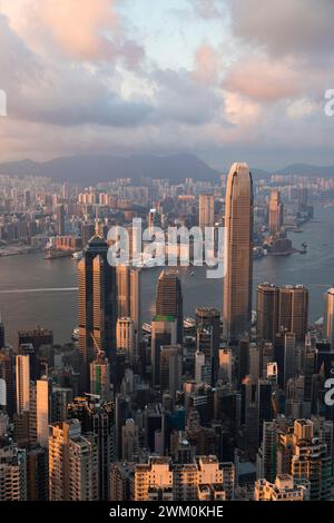 Victoria harbor near buildings in Hong Kong city under cloudy sky at sunset Stock Photo