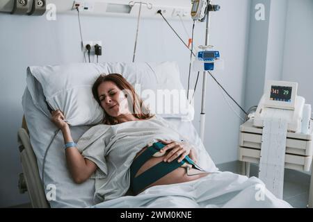 Pregnant woman in pain on bed at hospital Stock Photo