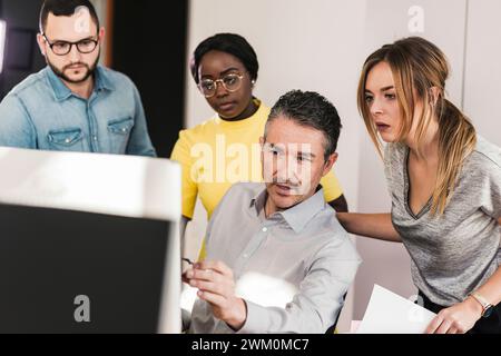 Businessman discussing over computer with colleagues in office Stock Photo