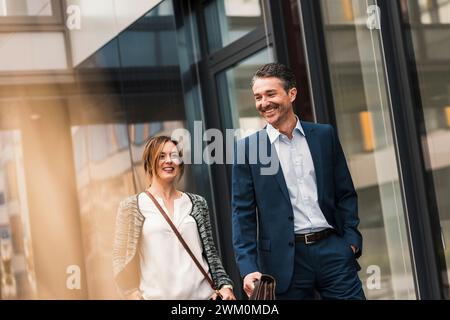 Happy coworkers walking near office building Stock Photo