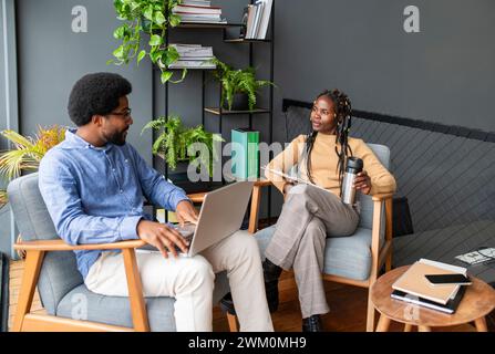 Businessman discussing with colleague sitting on armchair in office Stock Photo