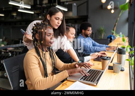 Businesswomen and businessmen working on laptops at desk Stock Photo