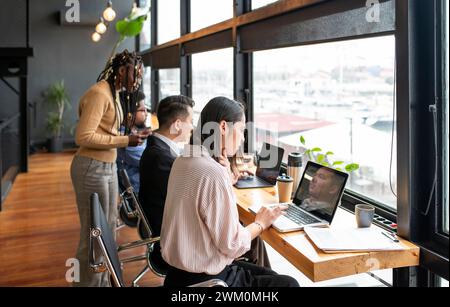 Businesswoman with colleagues using laptops at desk Stock Photo