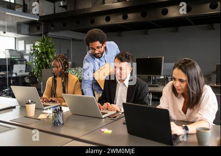 Young businessman discussing and planning with colleagues over laptop at desk Stock Photo