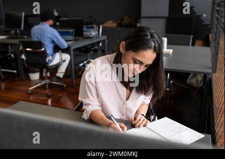 Businesswoman making notes in diary at desk Stock Photo