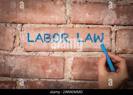 Labor Law. Text written with blue chalk on a red brick background. Stock Photo