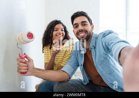 Playful couple with painting equipment taking selfie at new home Stock Photo
