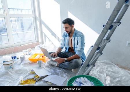 Young man using laptop in room under renovation Stock Photo