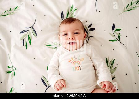 Smiling baby girl lying in bed at home Stock Photo