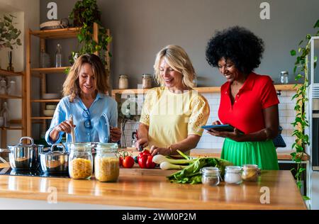 Happy friends cooking food together in kitchen at home Stock Photo