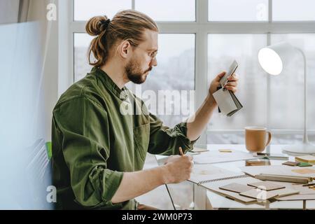 Furniture designer choosing color samples sitting at desk in office Stock Photo