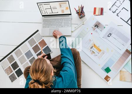 Interior designer sitting on floor and using laptop at office Stock Photo