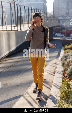 Happy mature woman gesturing and talking on smart phone Stock Photo
